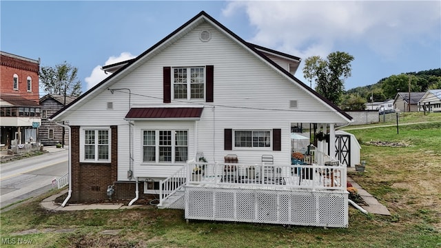 rear view of property featuring a lawn and a deck