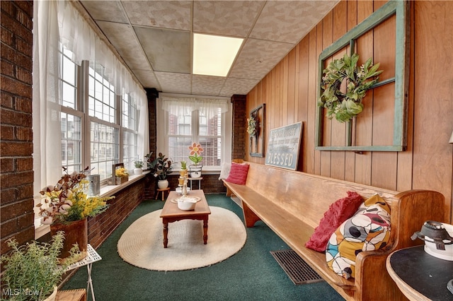 interior space featuring carpet, a drop ceiling, and wood walls