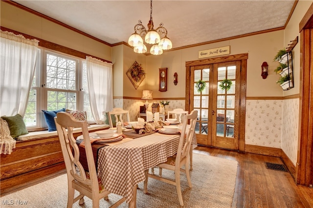 dining room with ornamental molding, a chandelier, french doors, and hardwood / wood-style flooring