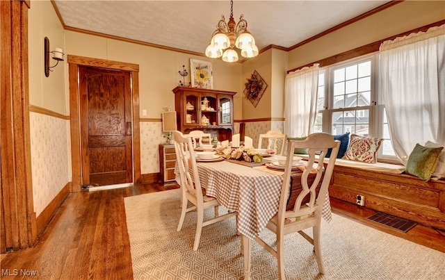 dining space featuring a notable chandelier, ornamental molding, and dark wood-type flooring