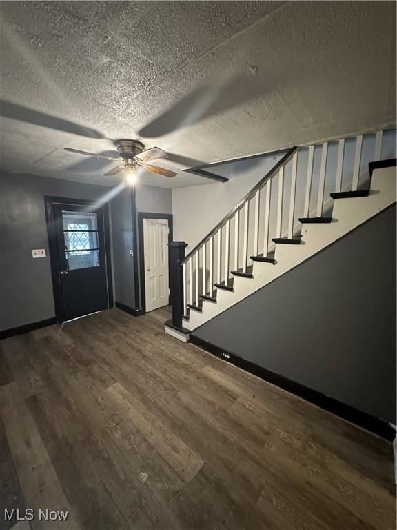 foyer entrance featuring ceiling fan, dark wood-type flooring, and a textured ceiling