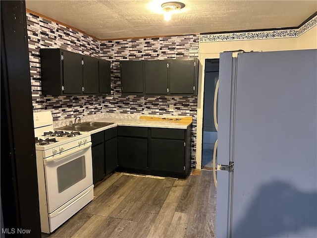 kitchen featuring dark wood-type flooring, sink, white appliances, and a textured ceiling