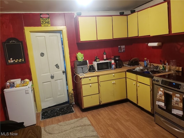 kitchen featuring sink, refrigerator, stainless steel electric range oven, and light wood-type flooring