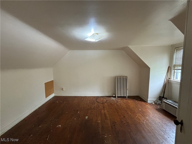 additional living space with radiator, lofted ceiling, and dark wood-type flooring