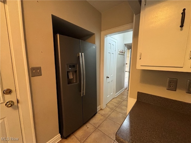 kitchen featuring stainless steel refrigerator with ice dispenser, white cabinetry, and light tile patterned flooring