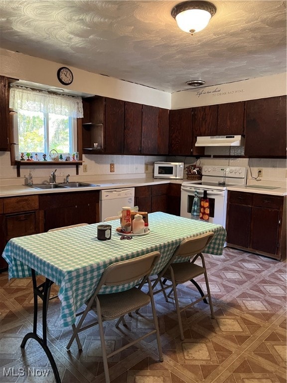 kitchen featuring light parquet flooring, dark brown cabinets, white appliances, and tasteful backsplash