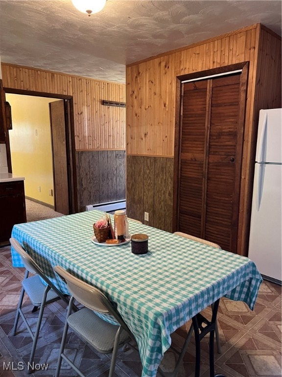 dining space featuring wood walls, a baseboard heating unit, and dark parquet flooring