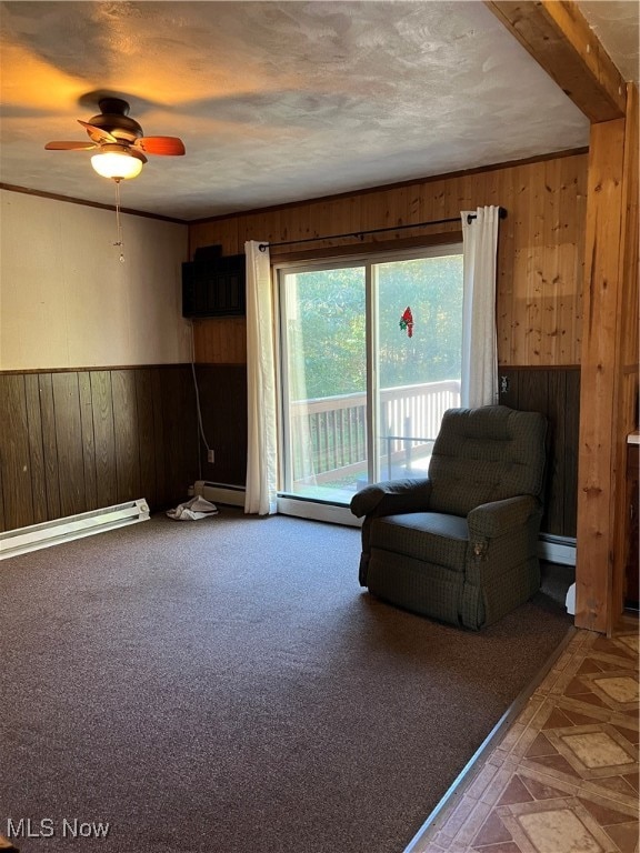 sitting room with a baseboard radiator, ceiling fan, and wood walls