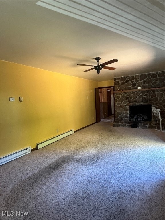 unfurnished living room with baseboard heating, a stone fireplace, carpet flooring, and ceiling fan