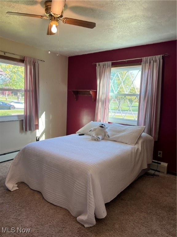 carpeted bedroom with ceiling fan, a textured ceiling, and baseboard heating