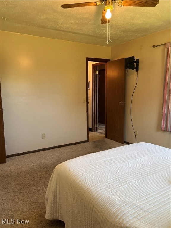 carpeted bedroom featuring a textured ceiling and ceiling fan