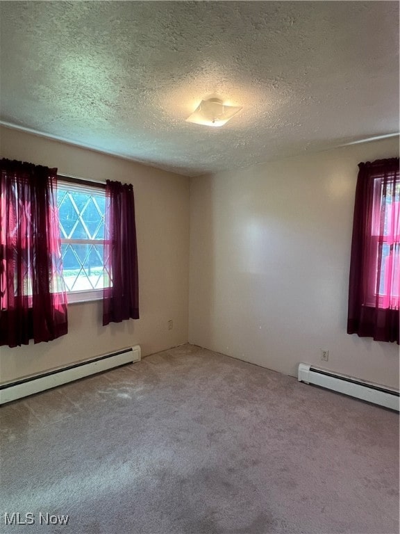 carpeted empty room with a textured ceiling and a baseboard heating unit