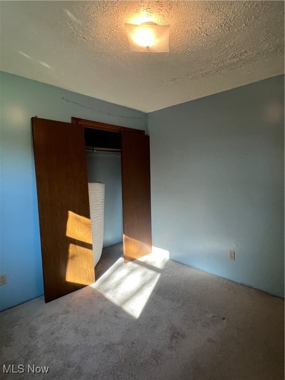 unfurnished bedroom featuring a closet, a textured ceiling, and carpet floors