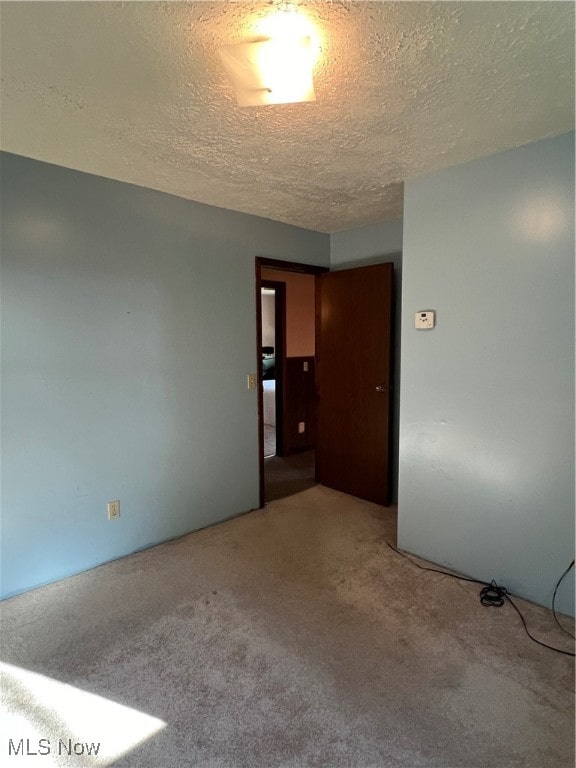 carpeted empty room featuring a textured ceiling