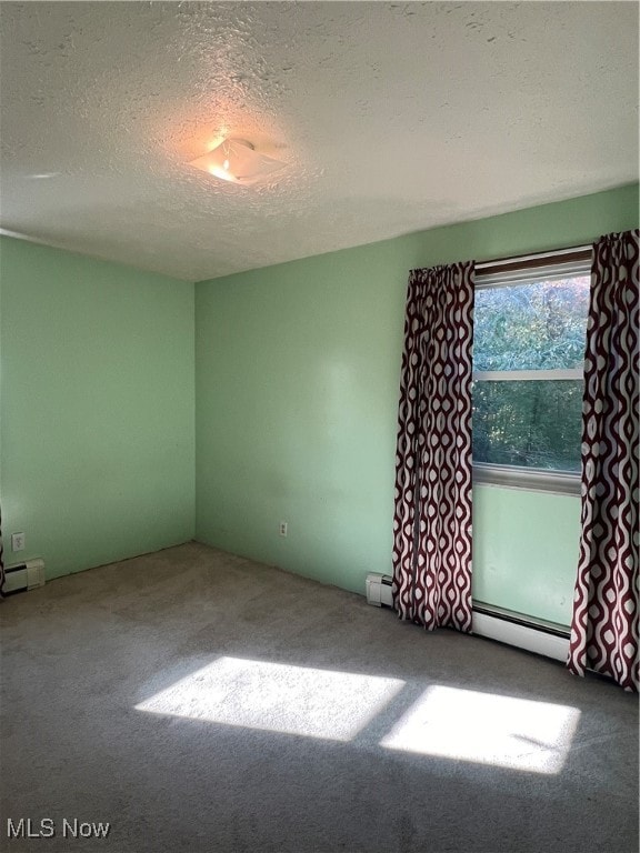 carpeted empty room featuring a textured ceiling and baseboard heating