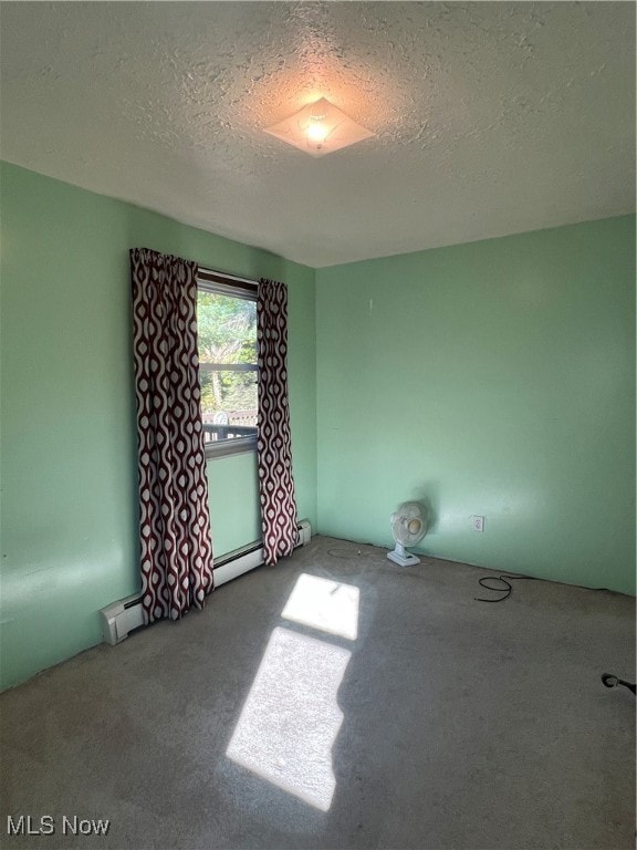 carpeted empty room featuring a textured ceiling and baseboard heating