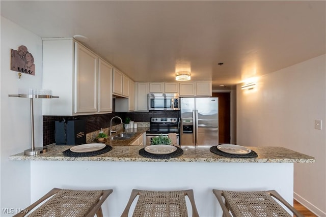 1133 W 9th St Unit 701, Cleveland, OH 44113 - kitchen featuring appliances with stainless steel finishes, a sink, a peninsula, light stone countertops, and decorative backsplash