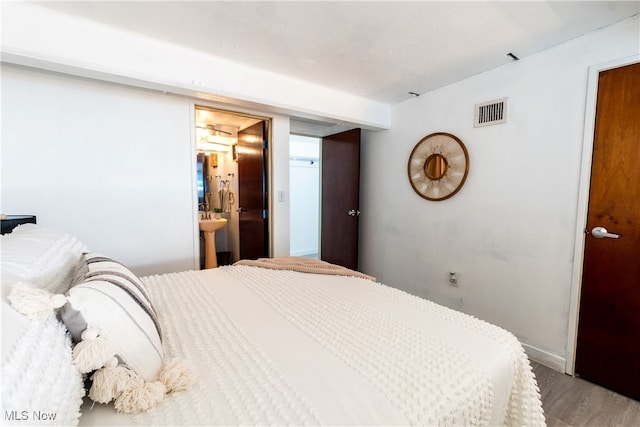 bedroom featuring connected bathroom and wood-type flooring