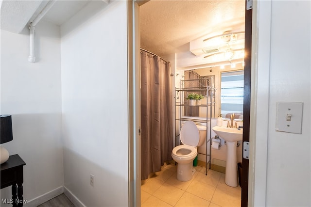 bathroom featuring a textured ceiling, tile patterned flooring, and toilet