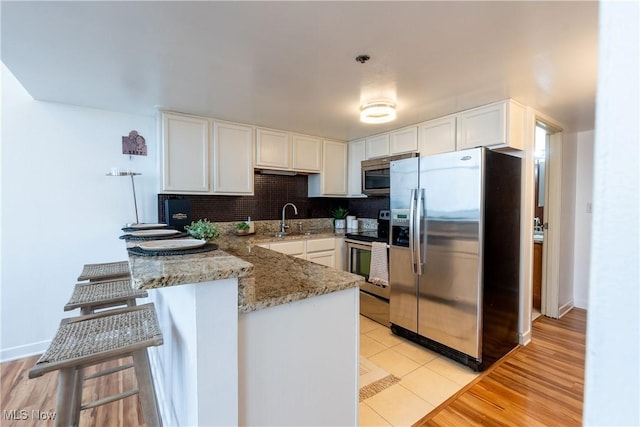 1133 W 9th St Unit 701, Cleveland, OH 44113 - kitchen featuring stainless steel appliances, a sink, white cabinetry, a peninsula, and light stone countertops