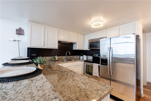 kitchen with appliances with stainless steel finishes, decorative backsplash, light hardwood / wood-style floors, white cabinetry, and sink