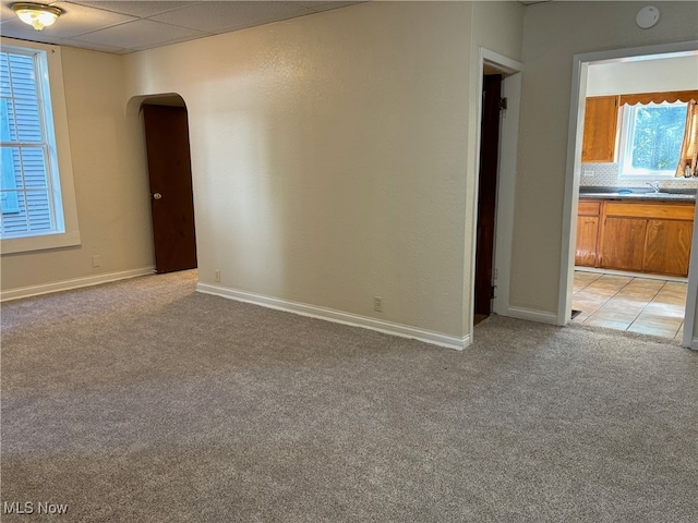 carpeted empty room featuring a paneled ceiling and sink