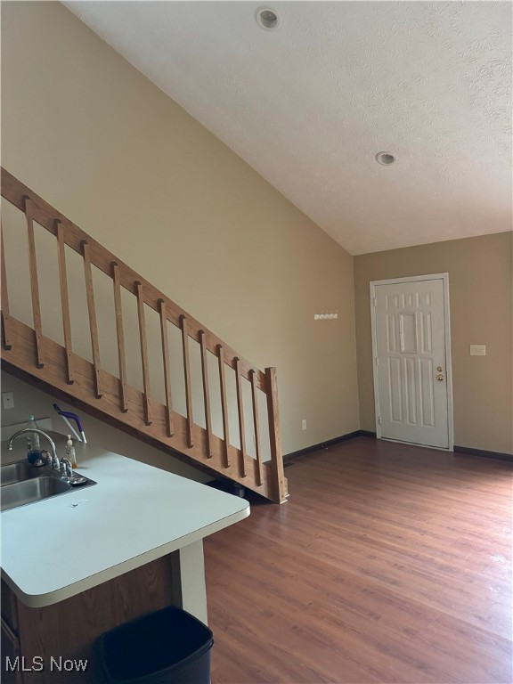 stairs featuring a textured ceiling, vaulted ceiling, sink, and hardwood / wood-style flooring