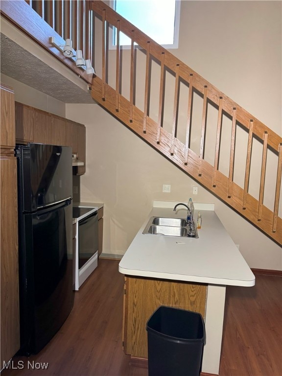 kitchen featuring kitchen peninsula, dark hardwood / wood-style flooring, white range with electric stovetop, sink, and black fridge