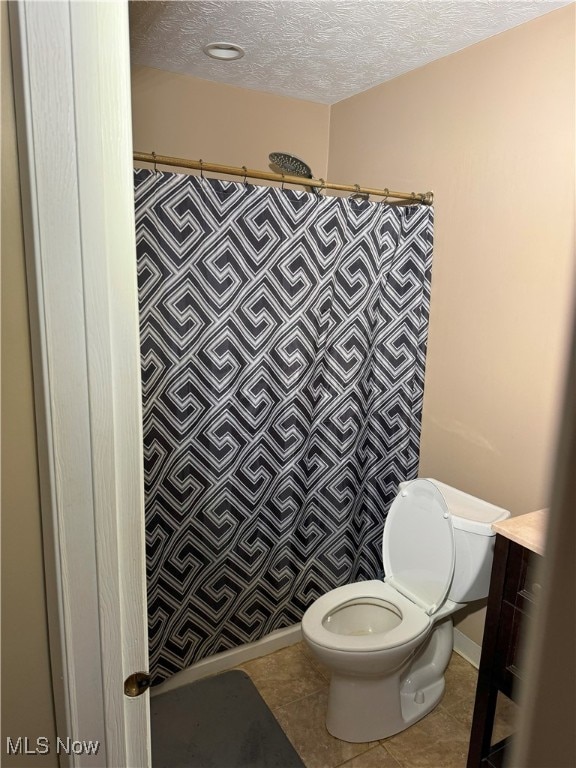 bathroom with tile patterned floors, a textured ceiling, curtained shower, and toilet