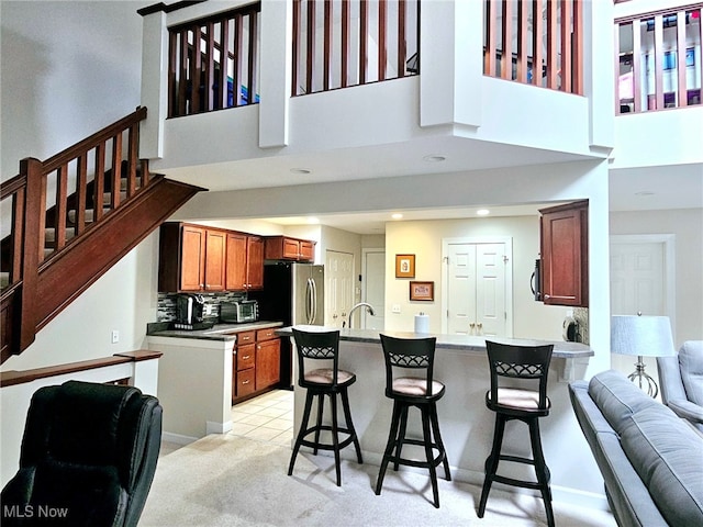 kitchen featuring sink, backsplash, a high ceiling, and a breakfast bar