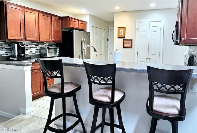 kitchen with stainless steel appliances, sink, a kitchen breakfast bar, and tasteful backsplash