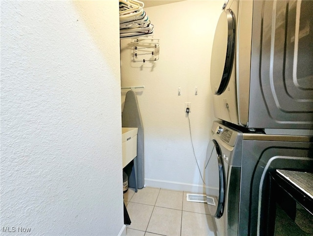 laundry room with light tile patterned floors and stacked washer and clothes dryer