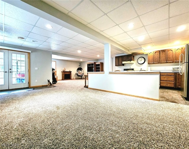 interior space with stainless steel refrigerator, kitchen peninsula, french doors, a paneled ceiling, and light carpet