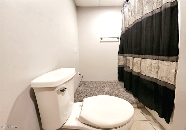 bathroom with a shower with curtain, toilet, and tile patterned floors