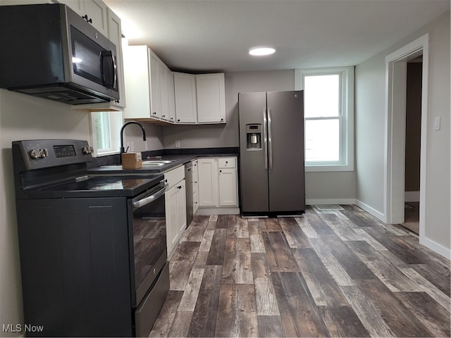 kitchen with white cabinets, appliances with stainless steel finishes, dark wood-type flooring, and sink