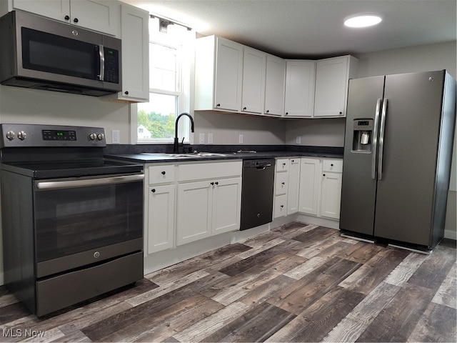 kitchen with stainless steel appliances, white cabinetry, dark hardwood / wood-style floors, and sink