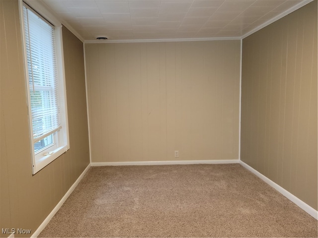 carpeted empty room featuring ornamental molding and wooden walls