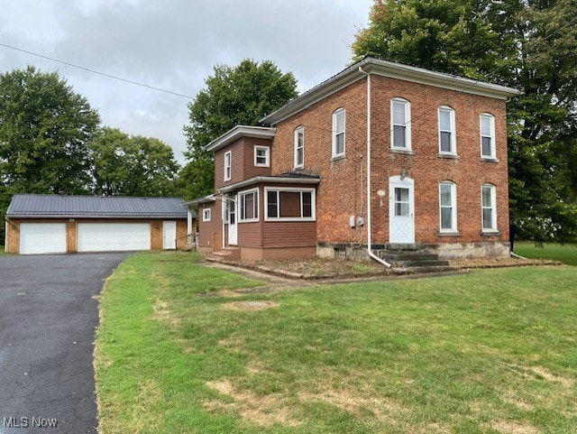 view of front of house with an outdoor structure, a front yard, and a garage