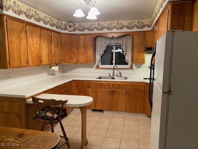 kitchen featuring pendant lighting, light tile patterned flooring, sink, a notable chandelier, and white fridge