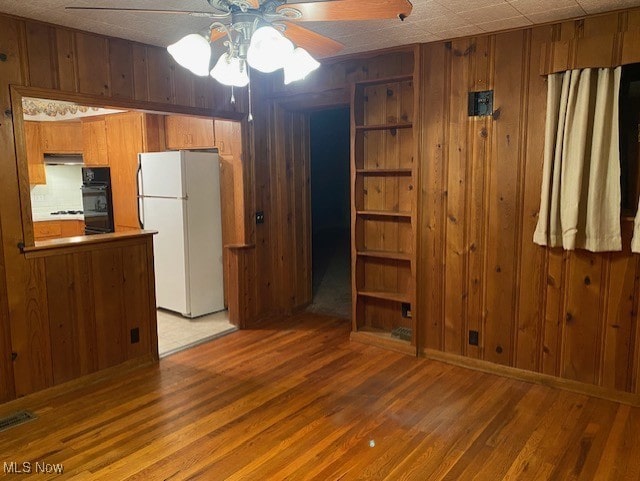 interior space featuring wood-type flooring, wood walls, and ceiling fan