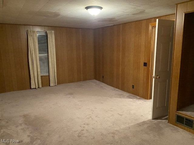 carpeted empty room featuring wood walls