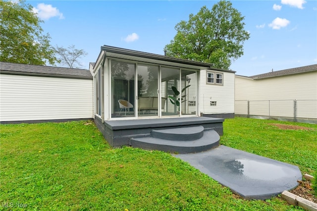 rear view of property featuring a lawn and a sunroom