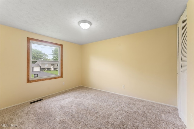 unfurnished bedroom featuring a textured ceiling, light carpet, and a closet