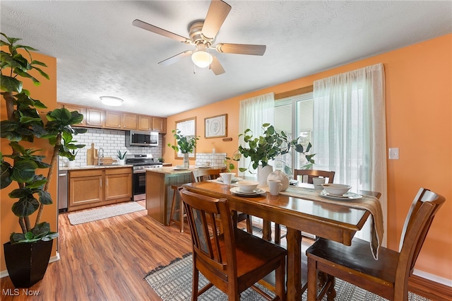 dining area featuring a textured ceiling, hardwood / wood-style floors, ceiling fan, and a wealth of natural light