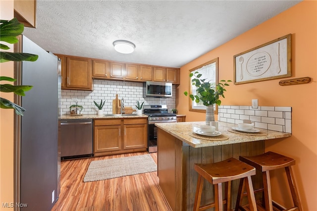 kitchen featuring kitchen peninsula, a breakfast bar area, stainless steel appliances, light hardwood / wood-style flooring, and sink