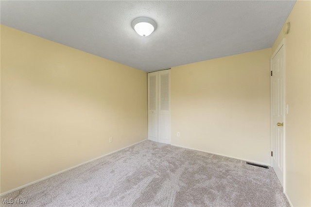 unfurnished room with a textured ceiling and carpet