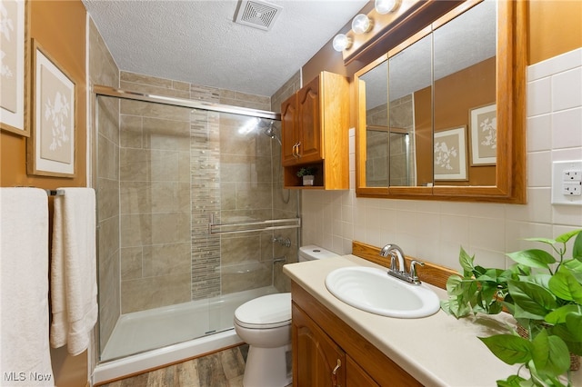 bathroom featuring tile walls, vanity, wood-type flooring, toilet, and an enclosed shower