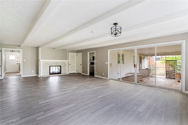 unfurnished living room with wood-type flooring, beam ceiling, and a textured ceiling