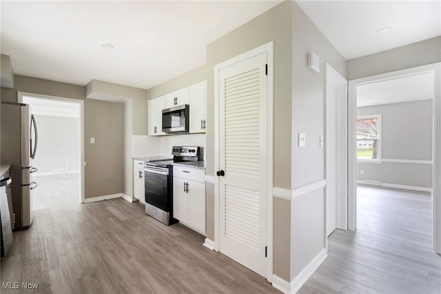 kitchen with light wood-type flooring, backsplash, stainless steel appliances, and white cabinets