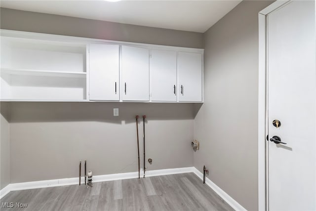 laundry area with light wood-type flooring, hookup for a gas dryer, washer hookup, and cabinets